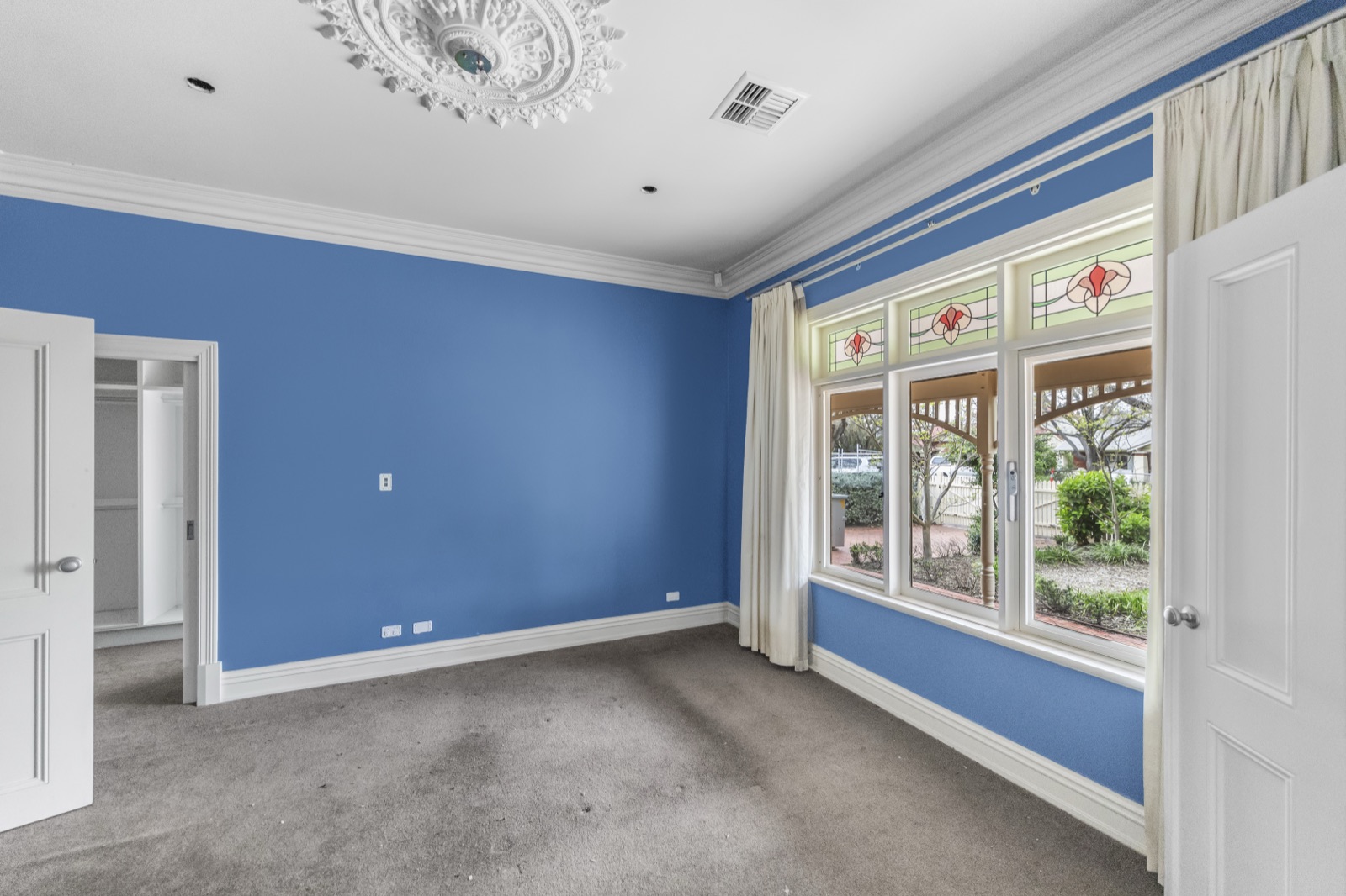 Dated bedroom with blue walls and bare grey carpet before renovation